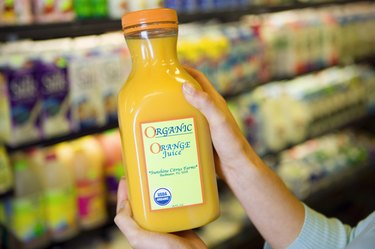 Person holding bottle of organic orange juice