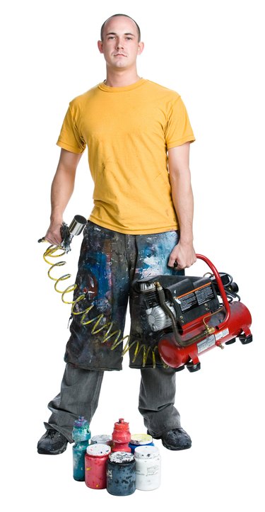 Man holding paint sprayer and air compressor