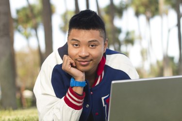 Student lying on grass with laptop