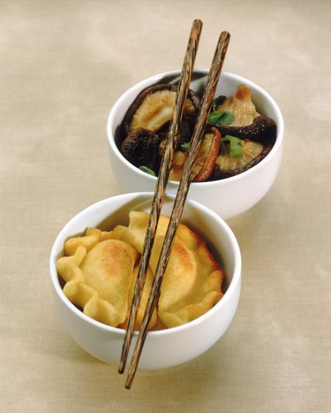 Chinese dumpling and mushroom with chopsticks in bowl, close-up
