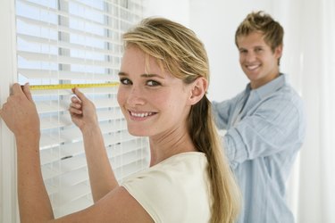 Couple measuring window blinds