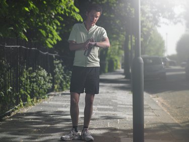 Mid adult man standing at street, looking at watch