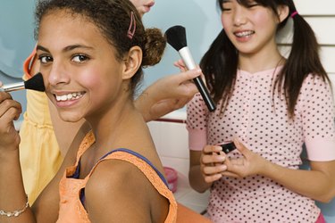 Two preteen girls applying makeup