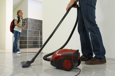 Girl watching father vacuum