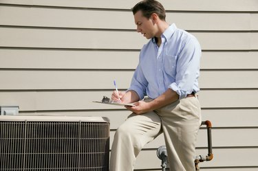 Man with clipboard near air conditioning unit