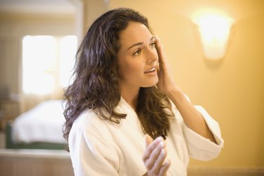 Woman applying lotion to face