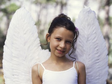 Girl (6-8) wearing angel wings, close up, portrait