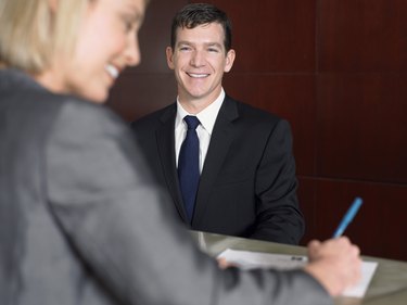 Businesswoman Smiles as She Signs a Document at a Reception Desk