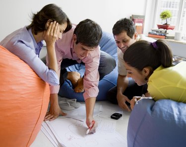 Businesspeople sitting in bean bag chairs and watching businessman write