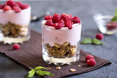 Homemade organic fresh parfait dessert with raspberries and granola, selective focus