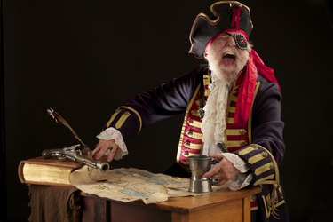 Laughing old pirate captain with treasure map holds pewter mug