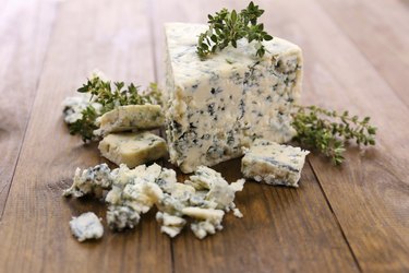 Tasty blue cheese with thyme, on wooden table