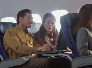 Business couple working on a laptop in an airplane