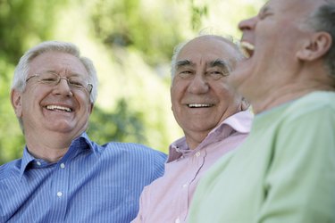 Three senior men laughing, close-up (focus on man wearing glasses)