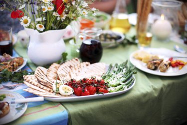 Grilled asparagus and tomatoes with pita bread on picnic table
