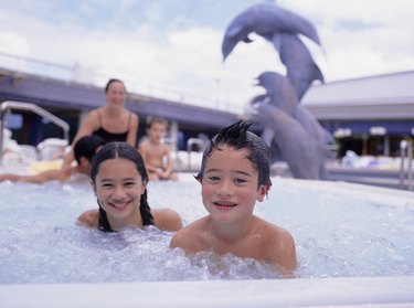 Two children (6-7), (10-11), posing in jacuzzi, portrait