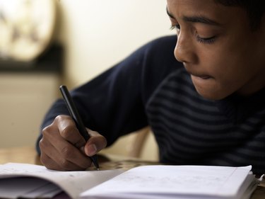 Close-up of boy (12-13) doing homework at desk