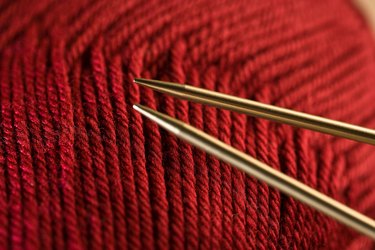 Knitting needles by red yarn