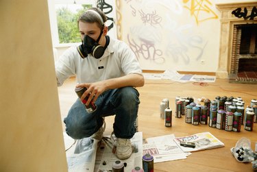 Young man wearing mask holding spray paint, close up