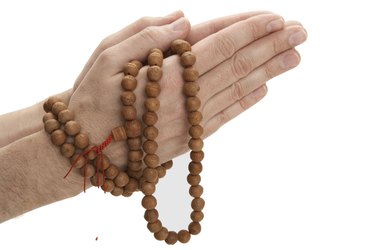 Man holding Buddhist prayer beads, close-up of hands