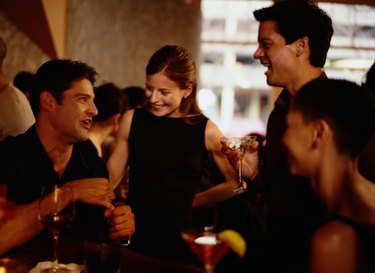 Two couples having cocktails at bar