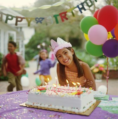 Girl (9-11) at birthday party, leaning over birthday cake, portrait