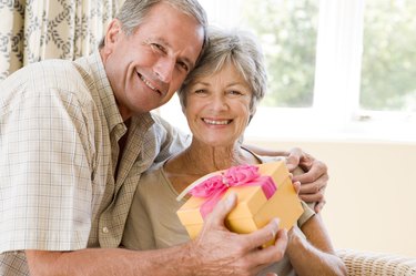 Husband giving wife gift in living room smiling