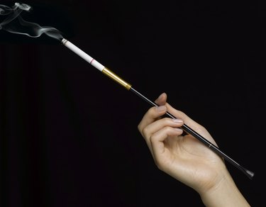 Woman holding cigarette in holder, close-up of hand