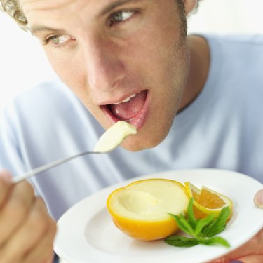 Close-up of a young man eating orange sorbet with a spoon