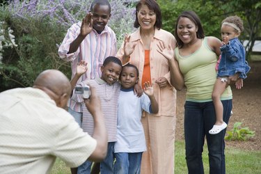 Rear view of a mature man taking a picture of his family members with a digital video camera