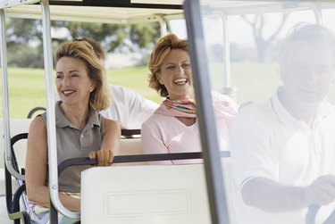 Smiling middle-aged women in golf cart