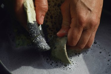 Artisan cleaning pot in sudsy liquid