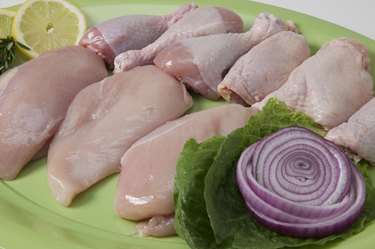 Platter of uncooked chicken breasts, thighs and legs