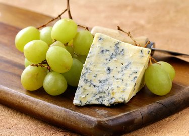 blue cheese and white grapes on a wooden board