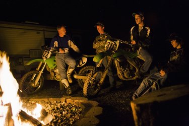 Riders on dirt bikes by campfire