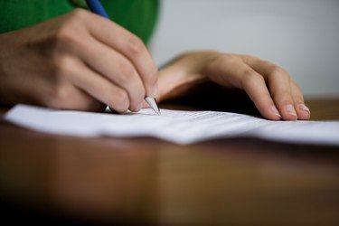 Hands writing with pen