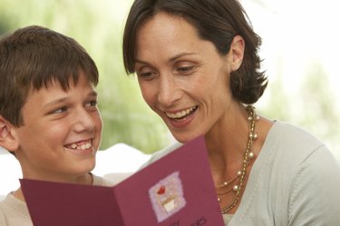 Mother and son (10-12) smiling, card in foreground