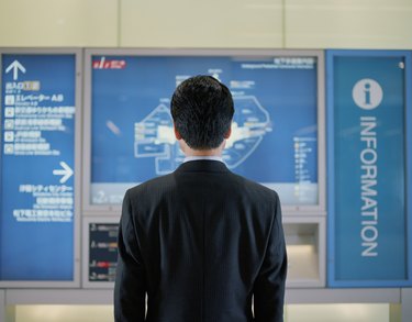 Mature businessman looking at map in subway station, rear view