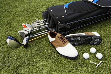 Golf clubs, golf bag, shoes, balls and tees on artificial turf