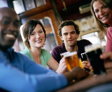 Friends at pub table, smiling, portrait (focus on man in centre)