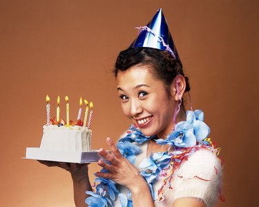 Young Woman Holding a Birthday Cake, Side View, Looking at Camera