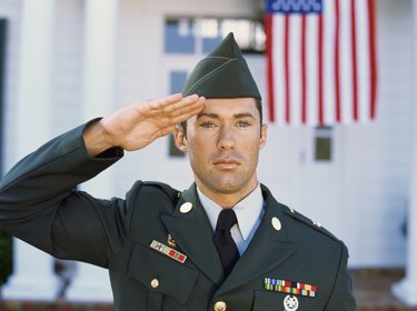 Close-up of a young man wearing a military uniform saluting