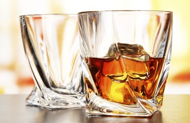 Glasses of whiskey, on bright background