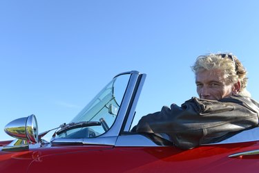 Portrait of mature man in red sports car