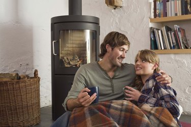 Couple snuggling by wood stove indoors