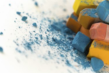 A close up photograph of a box of colorful used chalk pastels