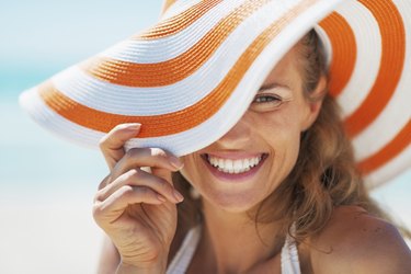 portrait of happy young woman in swimsuit and beach hat