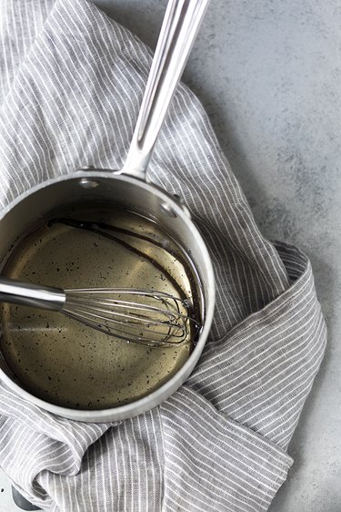 Pot of simple syrup and whisk on a kitchen cloth