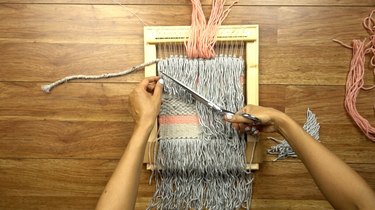Trimming fringe on woven wall hanging.