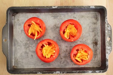 Hollowed-out tomatoes with grated cheese inside.